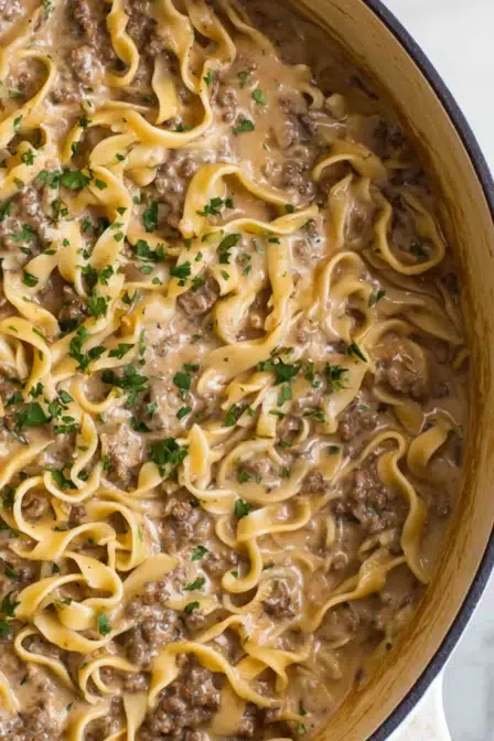 Close-up of creamy ground beef stroganoff with egg noodles in a rich sauce, sprinkled with fresh parsley.