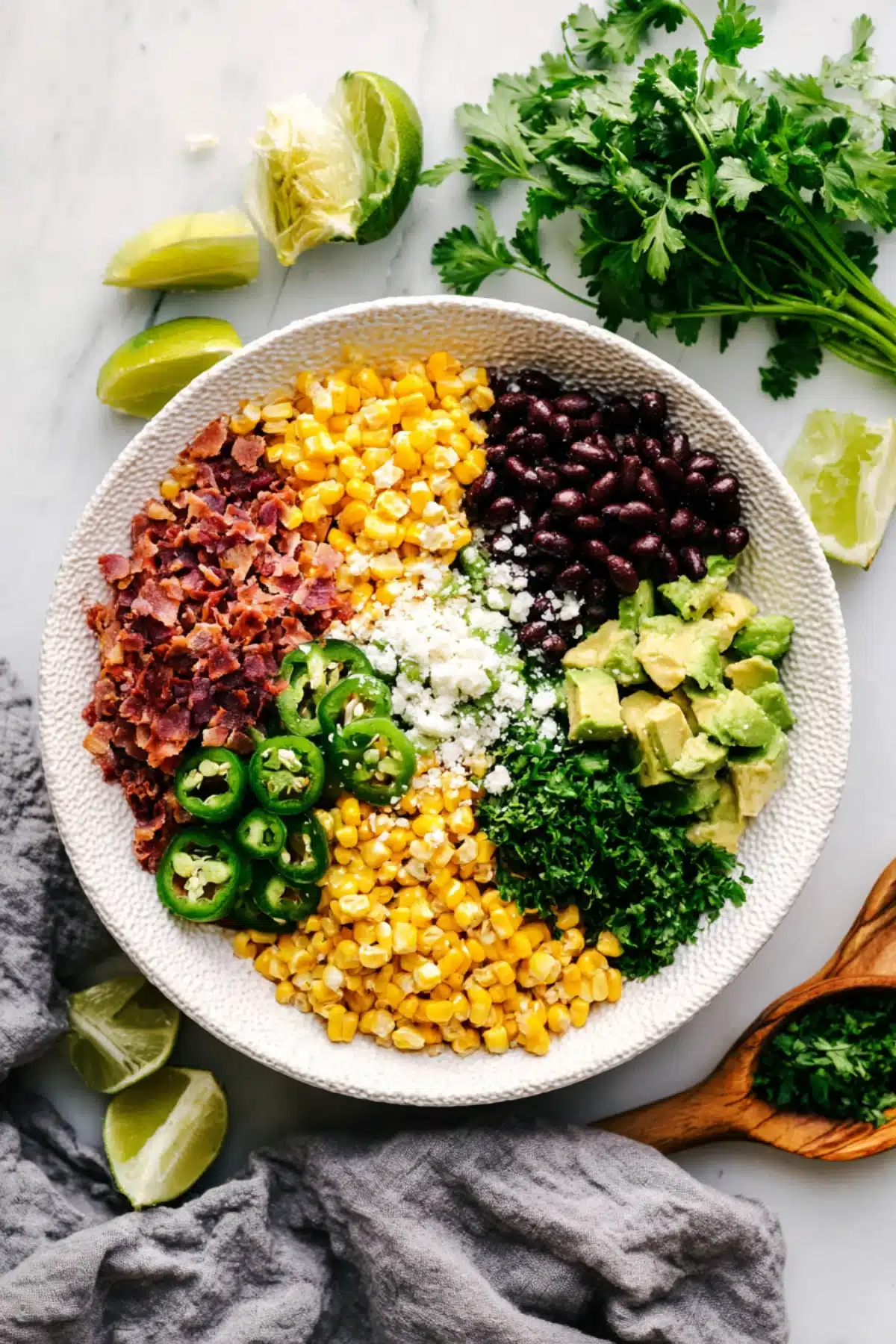Fresh ingredients for Mexican Street Corn Pasta Salad including corn, jalapeño, black beans, avocado, and bacon
