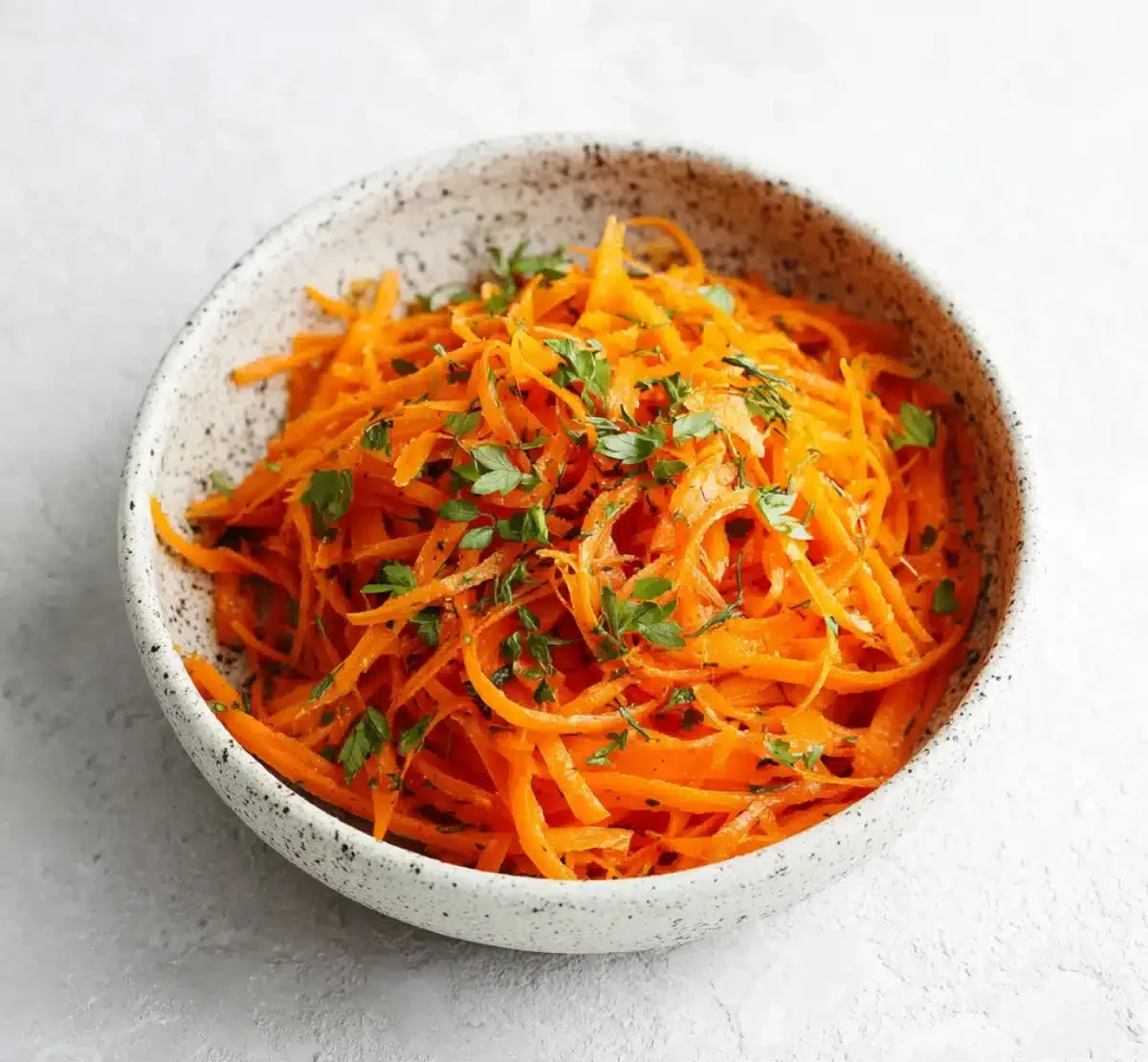 Carrot ribbons tossed with fresh mint in a ceramic bowl, ideal for Ray Peat’s raw carrot salad to support gut health