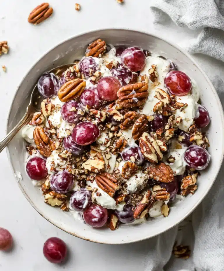 Sweet grape salad with creamy dressing and chopped pecans served in a white bowl on a light countertop