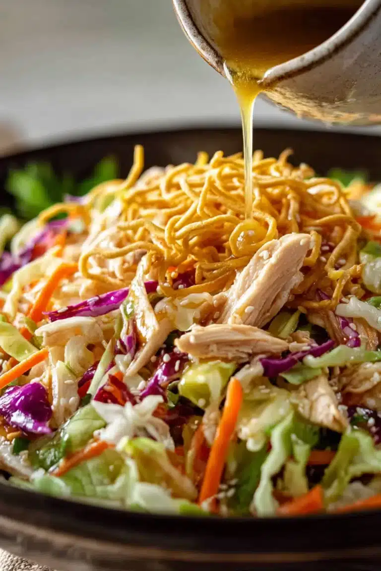 Fresh Chinese chicken salad with crispy noodles, shredded chicken, and colorful vegetables topped with dressing.