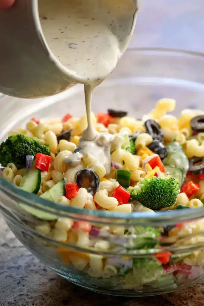  Creamy dressing poured over pasta salad with fresh vegetables and black olives.

