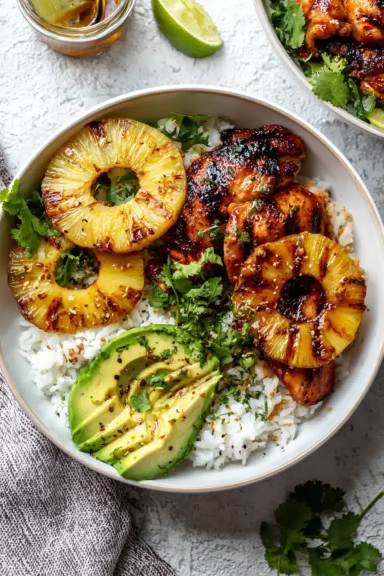 Grilled Hawaiian BBQ chicken with pineapple, avocado slices, and cilantro over steamed white rice in a bowl