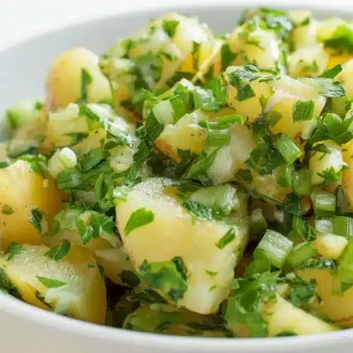 Lebanese potato salad with parsley, green onions, olive oil, and lemon juice served in a white bowl