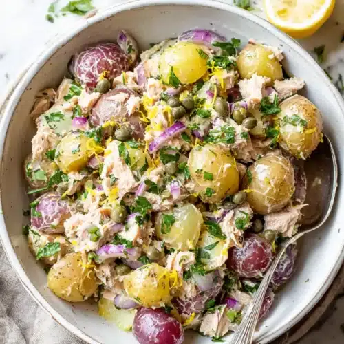 Colorful tuna potato salad with red and yellow potatoes, capers, red onions, lemon zest, and fresh parsley