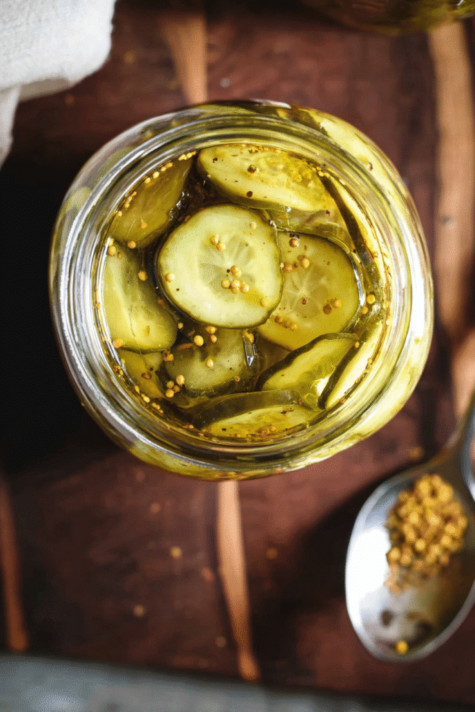 Crisp cucumber slices with mustard seeds in sweet tangy brine, packed in a glass jar for bread and butter pickles