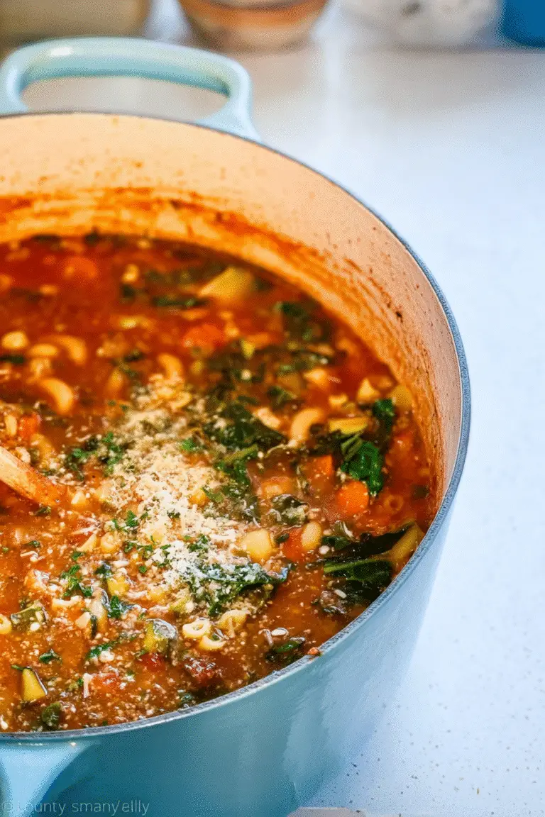 Longevity Soup simmering in a light blue Dutch oven, hearty tomato-based broth filled with pasta