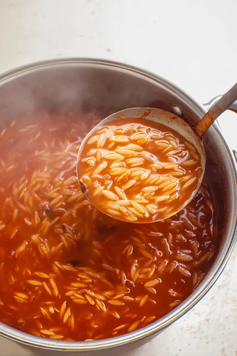 Quick Tomato Orzo Soup simmering in a stainless steel pot rich red tomato broth with tender orzo pasta,