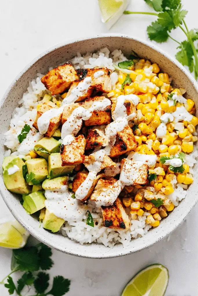 Street Corn Chicken Rice Bowl, top-down view, grilled chicken cubes over fluffy white rice, sweet roasted corn, diced avocado, fresh cilantro